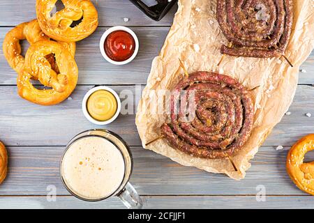 Speisekarte für das Oktoberfest. Wurst mit verschiedenen Soßen, Brezel und Glas dunklem Bier Stockfoto