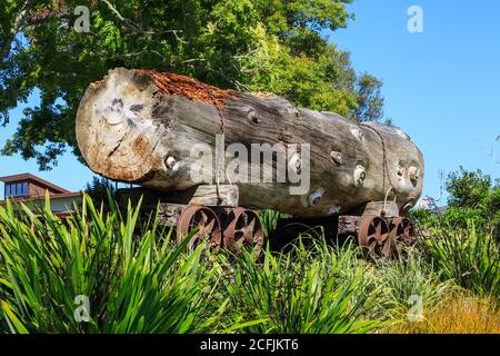 Ein alter Eisenbahnwagen mit einem massiven Kauri-Baumstamm. Fotografiert in einem Park in Katikati, Neuseeland Stockfoto