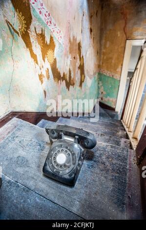 Altes Vintage-Telefon auf der Treppe eines alten verfallenen verlassenen Gebäudes Stockfoto