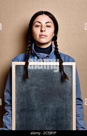 Mädchen ohne Make-up hält eine Tafel, und blaue Jacke, mit der gleichen Frisur wie Greta Thunberg, Studio auf braunem Karton Hintergrund gedreht Stockfoto