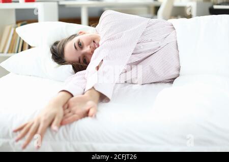 Frau liegt im Bett im Hemd und lächelt. Nahaufnahme Stockfoto