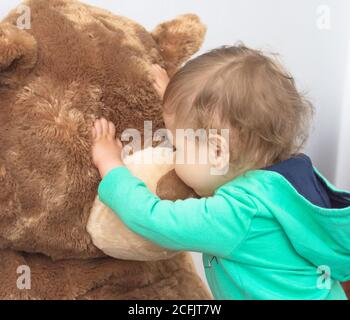 Nettes Kind, das Spaß hat, mit seinem riesigen Teddybären zu Hause zu spielen Stockfoto