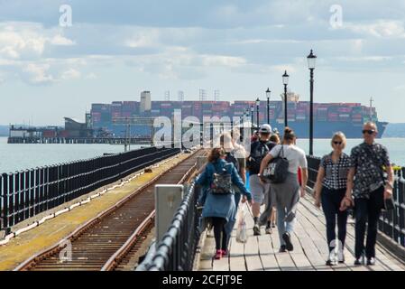 Southend Pier, Southend on Sea, Essex, Großbritannien. September 2020. Die HMM Hamburg ist ein Containerschiff der Algeciras-Klasse, eine Gruppe von sieben Frachtschiffen, die gleichermaßen die größten Containerschiffe der Welt sind und fast 24.000 Container transportieren können. HMM Hamburg wurde im Juli 2020 in Dienst gestellt und wird regelmäßig zwischen Asien und Europa reisen, wobei sie erstmals in der Themsmündung zum DP World London Gateway in Stanford le Hope, Essex, ankommt. Man sieht sie am Southend Pier vorbei mit Menschen, die auf dem Gehweg laufen Stockfoto