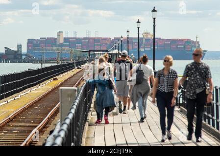 Southend Pier, Southend on Sea, Essex, Großbritannien. September 2020. Die HMM Hamburg ist ein Containerschiff der Algeciras-Klasse, eine Gruppe von sieben Frachtschiffen, die gleichermaßen die größten Containerschiffe der Welt sind und fast 24.000 Container transportieren können. HMM Hamburg wurde im Juli 2020 in Dienst gestellt und wird regelmäßig zwischen Asien und Europa reisen, wobei sie erstmals in der Themsmündung zum DP World London Gateway in Stanford le Hope, Essex, ankommt. Man sieht sie am Southend Pier vorbei mit Menschen, die auf dem Gehweg laufen Stockfoto