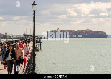 Southend Pier, Southend on Sea, Essex, Großbritannien. September 2020. Die HMM Hamburg ist ein Containerschiff der Algeciras-Klasse, eine Gruppe von sieben Frachtschiffen, die gleichermaßen die größten Containerschiffe der Welt sind und fast 24.000 Container transportieren können. HMM Hamburg wurde im Juli 2020 in Dienst gestellt und wird regelmäßig zwischen Asien und Europa reisen, wobei sie erstmals in der Themsmündung zum DP World London Gateway in Stanford le Hope, Essex, ankommt. Man sieht sie am Southend Pier vorbei mit Menschen, die auf dem Gehweg laufen Stockfoto