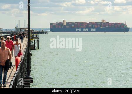 Southend Pier, Southend on Sea, Essex, Großbritannien. September 2020. Die HMM Hamburg ist ein Containerschiff der Algeciras-Klasse, eine Gruppe von sieben Frachtschiffen, die gleichermaßen die größten Containerschiffe der Welt sind und fast 24.000 Container transportieren können. HMM Hamburg wurde im Juli 2020 in Dienst gestellt und wird regelmäßig zwischen Asien und Europa reisen, wobei sie erstmals in der Themsmündung zum DP World London Gateway in Stanford le Hope, Essex, ankommt. Man sieht sie am Southend Pier vorbei mit Menschen, die auf dem Gehweg laufen Stockfoto