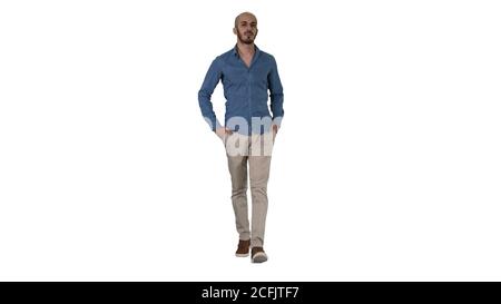 Schöner junger arabischer Mann trägt ein lässiges Outfit zu Fuß, indem seine beiden Hände in seine Taschen auf weißem Hintergrund. Stockfoto