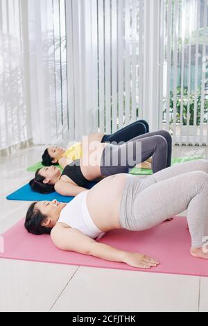 Schwangere Frauen tun Gesäßbrücke Stockfoto