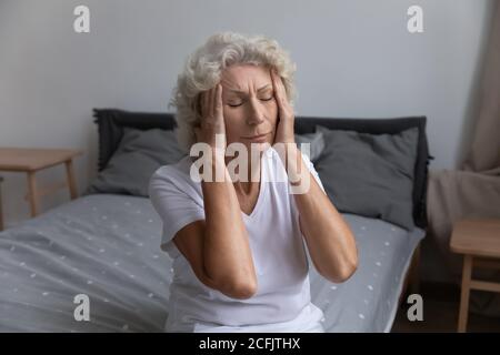 Unglücklich ungesunde reife Frau berühren Tempel, leiden unter Kopfschmerzen Stockfoto