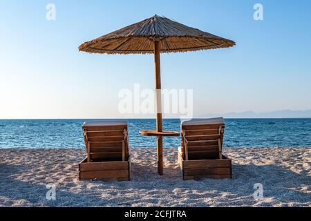 Ein schöner einsamer langer Sandstrand in heißer Sommersonne mit wolkenlosem blauen Himmel und Meer. Stockfoto