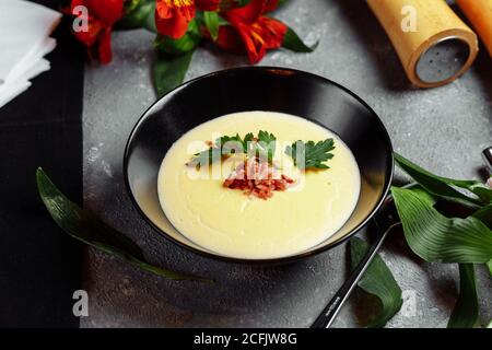 Schüssel mit leckeren Käse Sahne Suppe mit Speck auf einem Grauer Hintergrund Stockfoto