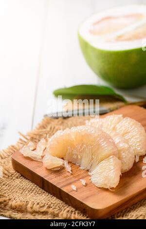 Frisch geschälte Pomelo oder Grapefruit auf Holzplatte. Saisonale Früchte Thailands, Pomelo oder Citrus grandis, geschält auf weißem Holz Hintergrund. Stockfoto