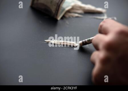 Weißes Pulver als Droge mit Geld auf schwarzer Oberfläche, Konzeptbild Stockfoto