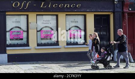 ELTERNGENEHMIGUNG GEGEBEN Leute gehen vorbei Paddy Dunne's, ein Pub in Athy, Co Kildare mit Plakaten Lobbying der irischen Regierung, um covid-19 Lockdown-Beschränkungen zu entspannen und ihnen zu erlauben, wieder zu öffnen. Stockfoto