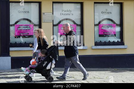 ELTERNGENEHMIGUNG GEGEBEN Leute gehen vorbei Paddy Dunne's, ein Pub in Athy, Co Kildare mit Plakaten Lobbying der irischen Regierung, um covid-19 Lockdown-Beschränkungen zu entspannen und ihnen zu erlauben, wieder zu öffnen. Stockfoto