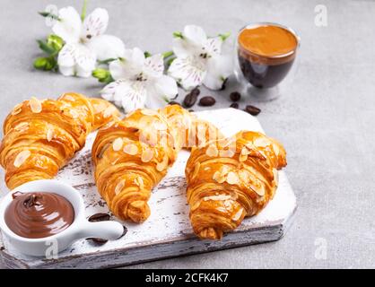 Lecker frisch drei Croissants, Mandeln in Scheiben geschnitten mit Kaffee und Schokoladenpaste. Stockfoto