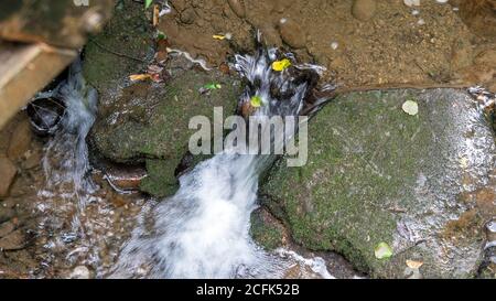 Fließendes Bachwasser zwischen zwei Steinen Stockfoto