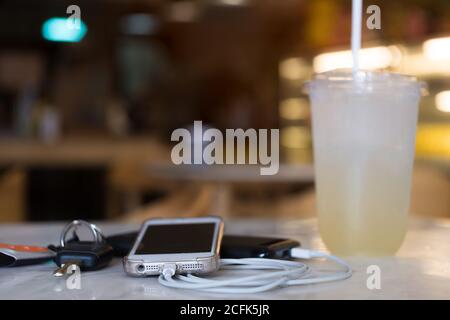 Smartphone aufladen mit Powerbank mit Limonade und Schlüssel Stockfoto