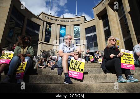 Demonstranten, die auf der Buchanan Street Steps in Glasgow sitzen, nehmen an einer Protestkundgebung für Flüchtlinge und Black Lives Matter Teil, die von Stand Up to Racism Scotland organisiert wird. Stockfoto