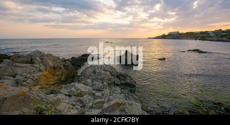 Sonnenuntergang an der Küste des schwarzen Meeres. Wunderbare dramatische Landschaft mit Felsen auf dem Kiesstrand unter einem bewölkten Himmel. Samt Saison Urlaub Stockfoto