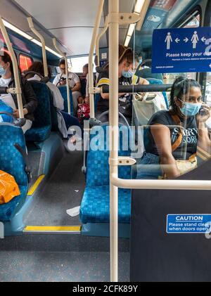 Fahrgäste in einem Bus tragen Gesichtsbezüge und versuchen, soziale Distanzierung nach Regierung Covid-19 Sicherheitsregeln für den öffentlichen Verkehr zu üben. Stockfoto