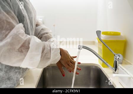 Seitenansicht der Ärztin im Schutzanzug Hände waschen Während der Vorbereitung auf den medizinischen Eingriff in der modernen Klinik Stockfoto