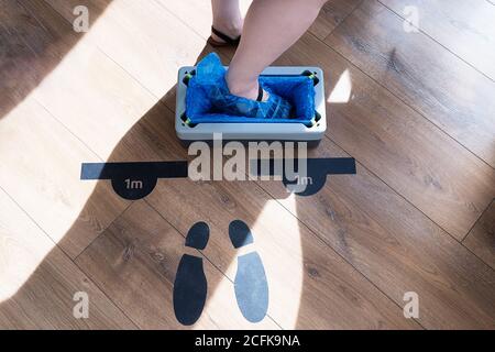 Von oben der Ernte anonyme weibliche Besucher Schritt auf automatische Gerät für Schuhüberzüge am Eingang der Klinik platziert Stockfoto