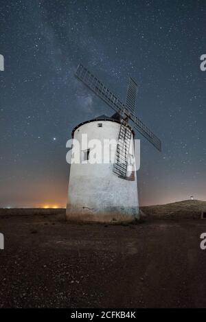 Niedriger Winkel der alten weißen Windmühle Turm auf einem Hügel Gegen Sternenhimmel mit Milchstraße Stockfoto