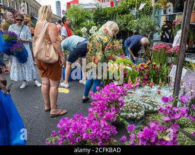 Besucher und Touristen kaufen Blumen von den Händlern in Columbia Road Blumenmarkt. Stockfoto