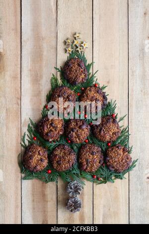 Draufsicht auf Weihnachtsbaum mit grünen Fichtenzweigen Und süße Schokoladenkekse auf Holzplankenfläche angeordnet Stockfoto
