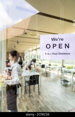 Wiedereröffnung Restaurant Beschilderung mit sozialen Abstand für neue normale Restaurant mit Hintergrund der asiatischen Kellner und Kellnerin bereiten Restaurant vor op Stockfoto