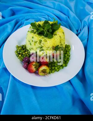 Reissalat. Dekoriert mit Oliven und Erdbeeren. Auf einem blauen Stoffhintergrund Stockfoto