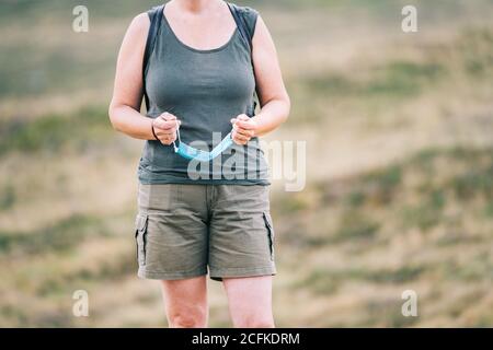 Anonyme Reisende Frau, die eine medizinische Gesichtsmaske in den Händen hält Stockfoto