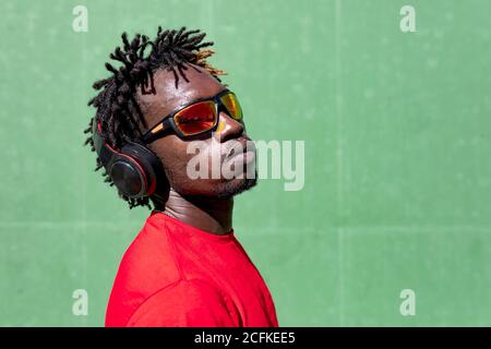 Seitenansicht des ernsthaften afroamerikanischen männlichen Athleten, der zuhört Musik in Kopfhörern während der Vorbereitung auf das Training im Sommer Stockfoto