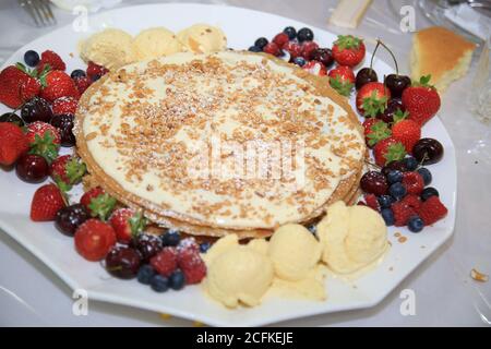 Close-up leckere Pfannkuchen mit frischen Heidelbeeren, Erdbeeren und Ahornsirup auf einem hellen Hintergrund. Mit kopieren. Süßes Ahornsirup fließt aus Stockfoto