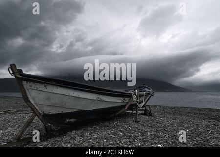 Altes Ruderboot und dramatische Sturmwolken rund um den Gipfel von Hólmatindur Stockfoto