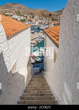 Treppe mit Aussicht, Hydra Island, Griechenland. Mit Blick auf den Hafen, Insel Hydra, Griechenland. Symmetrisch weiß getünchte Wände führen zum blauen Meer. Stockfoto
