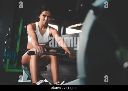 Konzentriertes athletisches Mädchen, das Übung auf dem Rudergerät tut Stockfoto