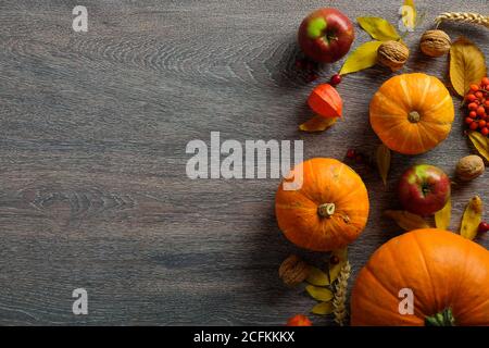 Herbstkomposition. Kürbisse, herbstliche Früchte, trockene Blätter auf dunklem Holztisch. Flach liegend, Draufsicht, Kopierbereich. Erntedankfest oder Erntedankfest Konzept. Stockfoto