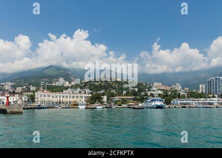 JALTA, KRIM, RUSSLAND - Mai 29.2014: Blick auf die Promenade und den Pier und die Stadt selbst am Fuße der Krimberge vom Meer. A c Stockfoto