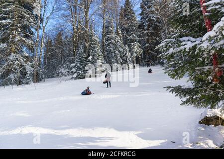 Russland, die Hochebene Lago-Naki, Adygeya Republik - Januar 28.2017: Das Kind rollt auf einem aufblasbaren Schlauch einen Schneehugel hinunter zum Skifahren. Sonniger Wintertag Stockfoto