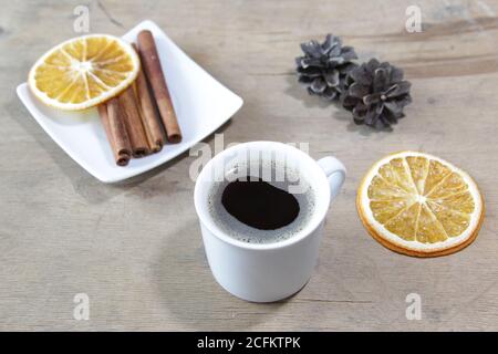 Lebensmittelkomposition mit Tasse Kaffee, Zimtstangen, Orangen und Tannenzapfen auf einem hölzernen Hintergrund. Flatlay. Draufsicht. Stockfoto
