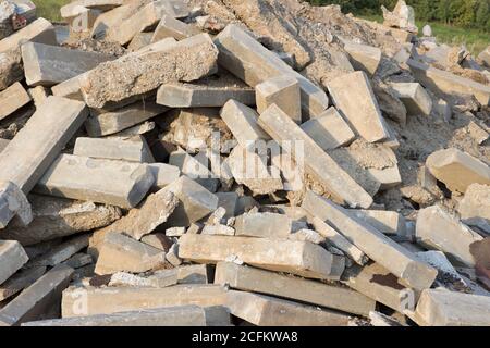 Ein großer Haufen von Felsen, Betonblöcken und Sand gegen den blauen Himmel. Bauabfälle, Betonreste aus dem Abriss, Straße. Stockfoto