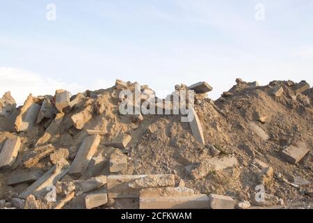 Ein großer Haufen von Felsen, Betonblöcken und Sand gegen den blauen Himmel. Bauabfälle, Betonreste aus dem Abriss, Straße. Stockfoto
