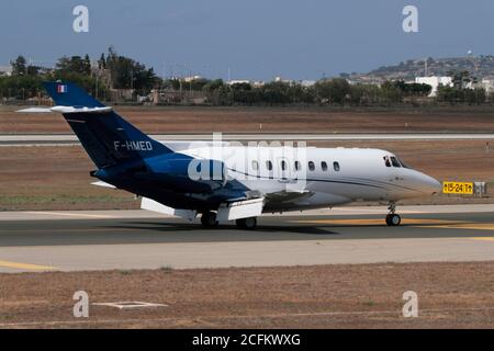 British Aerospace 125-1000 (Raytheon Hawker 1000) Business Jet rollt bei der Ankunft in Malta, mit Pilot winken aus Cockpit-Fenster. VIP-Flugreisen. Stockfoto