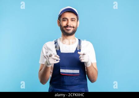 Hey, du! Fröhlicher Handwerker in Overalls und Hygienehandschuhen, die auf die Kamera zeigen. Beruf der Dienstleistungsbranche, Kurierversand, Housekeeping Wartung. Stockfoto