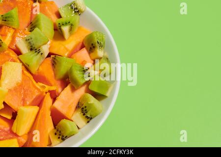 Nahaufnahme von köstlichen gesunden natürlichen Obstsalat mit gehackten Papaya Und Kiwi serviert in Teller auf hellgrünem Hintergrund platziert Stockfoto