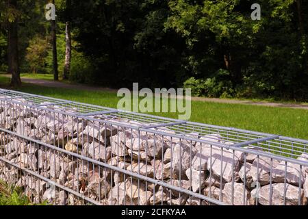 Trennung der Straße vom Parkgelände. Ein Fragment eines Zauns aus Gabionen. Stockfoto