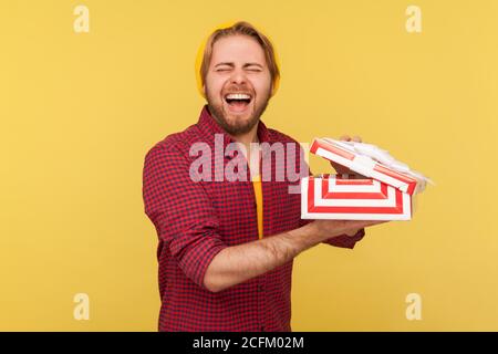 Überglücklich entzückt Hipster Kerl in Beanie Hut Eröffnung Geschenk-Box, lachen laut aufrichtig und überrascht, Gefühl aufgeregt durch ehrfürchtige Geburtstag Presen erstaunt Stockfoto