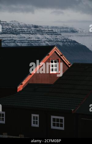 Holzhaus in Siedlung im Herbst auf den Färöern Auf verschneiten Bergen Stockfoto